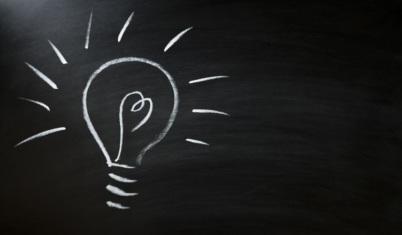 An image of a lightbulb drawn on a black chalkboard.