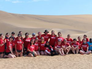 A large group of Brock students and staff pose in a sand dune in Namibia.