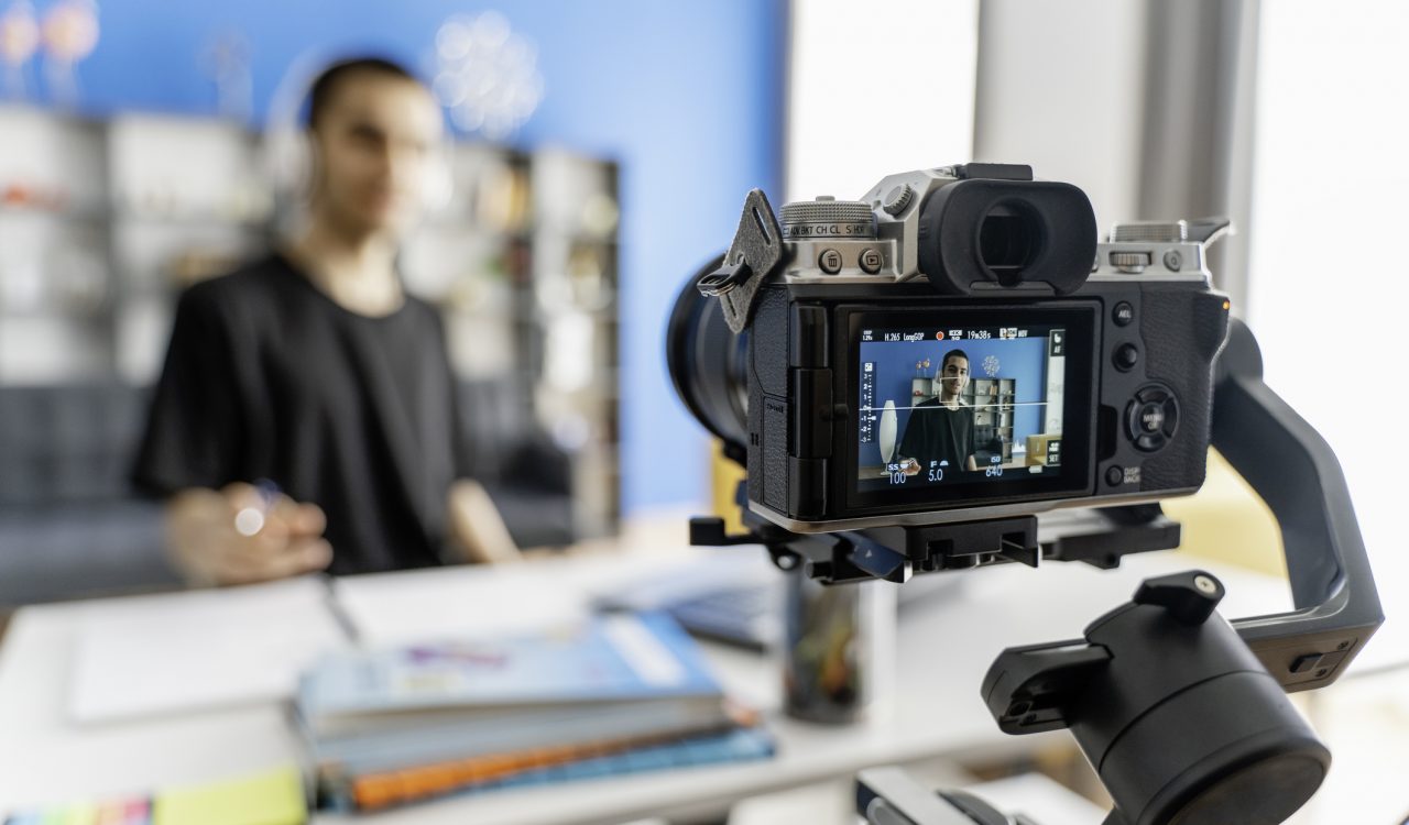 A student films himself using a camera on a tripod.