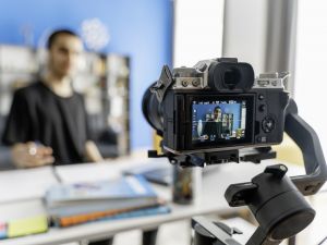 A student films himself using a camera on a tripod.