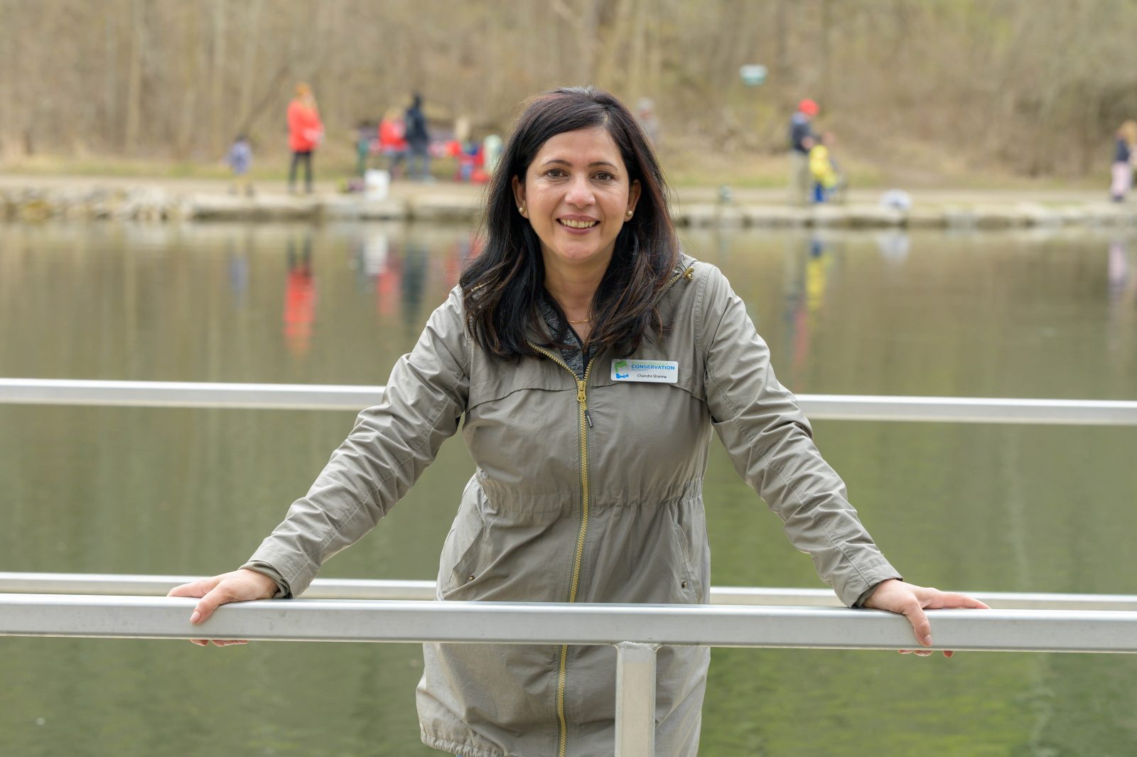 Chandra Sharma stands on a bridge with water and people in the background.