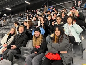 A large group of people sit in the stands of a hockey arena.