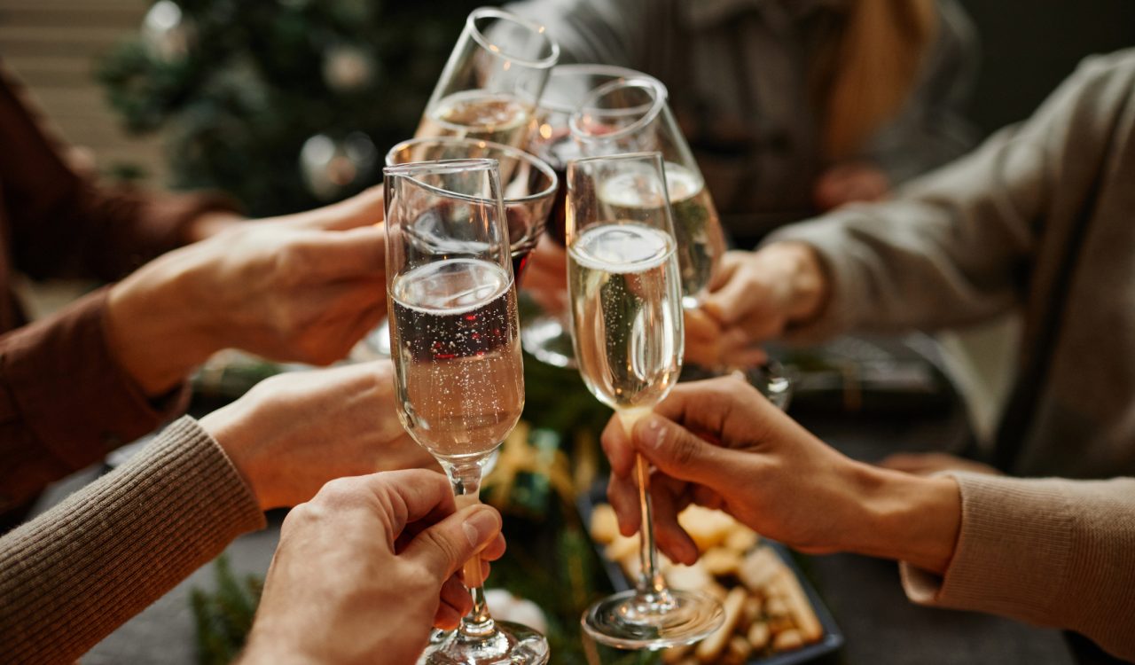 A group of six people toast with flutes of sparkling wine.