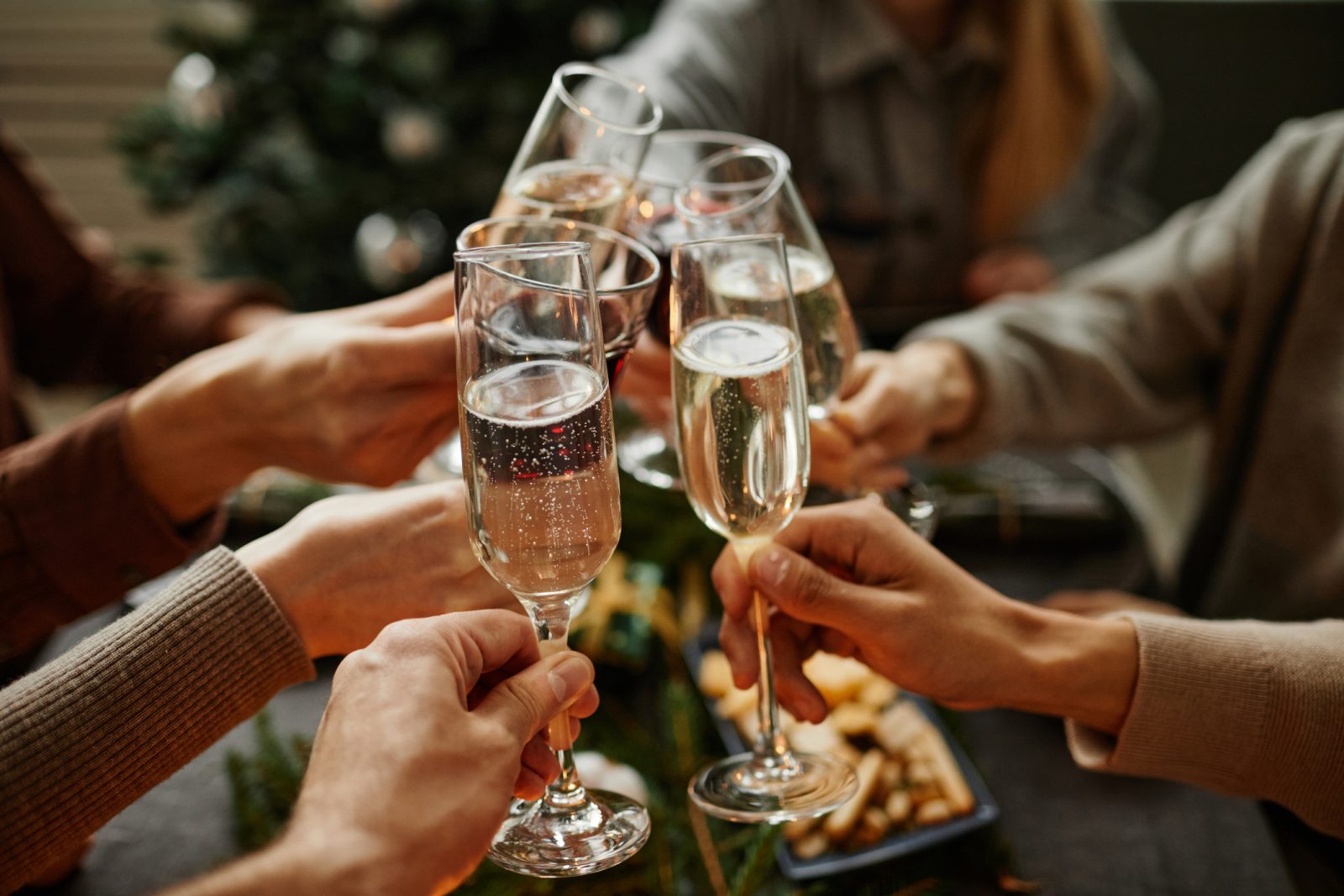 A group of six people toast with flutes of sparkling wine.