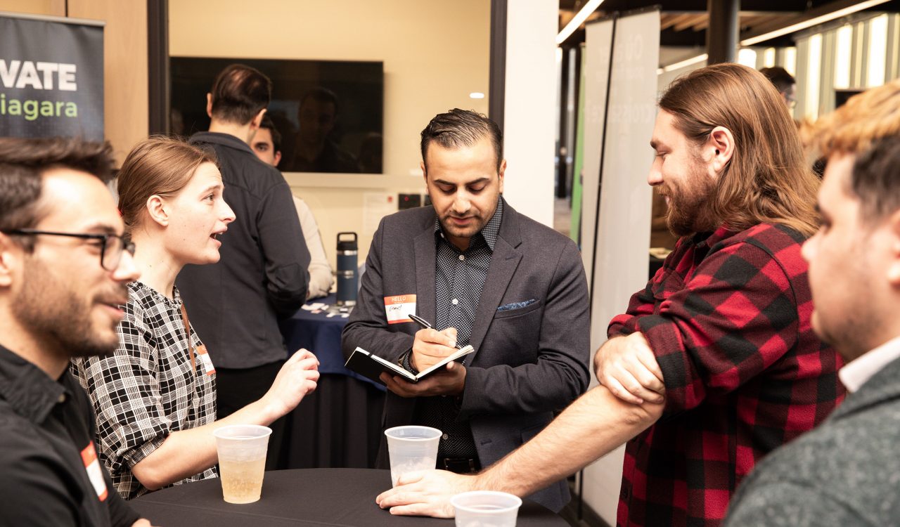 A group of people standing around a table having a conversation.