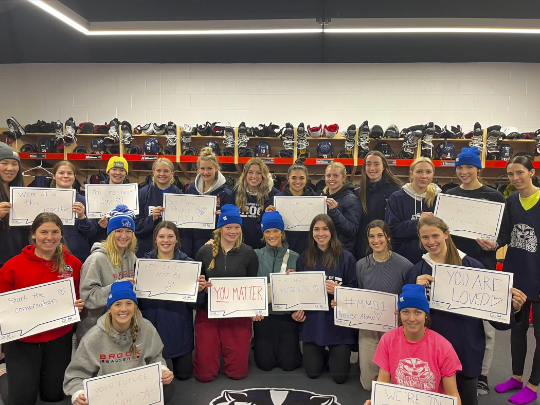 A group of women’s hockey players hold signs with positive messages.