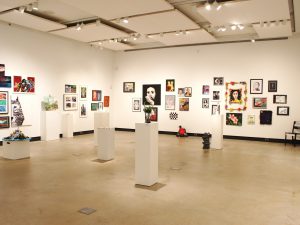 1. An art gallery with white walls filled with artwork with different mediums.