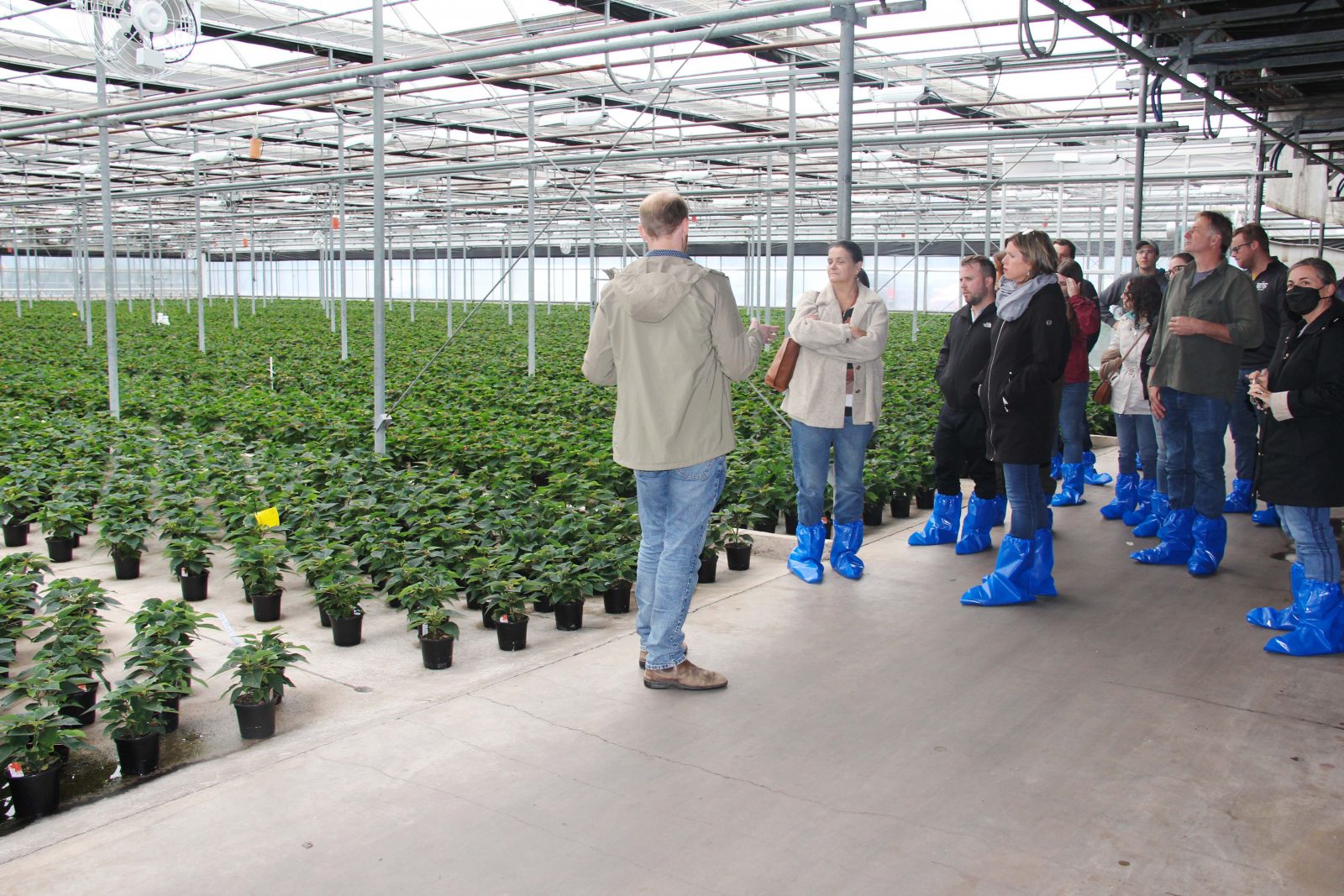 A man speaks to a group of people inside a greenhouse.