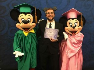 Jonah Graham holds an internship completion certificate while standing between Mickey and Minnie Mouse