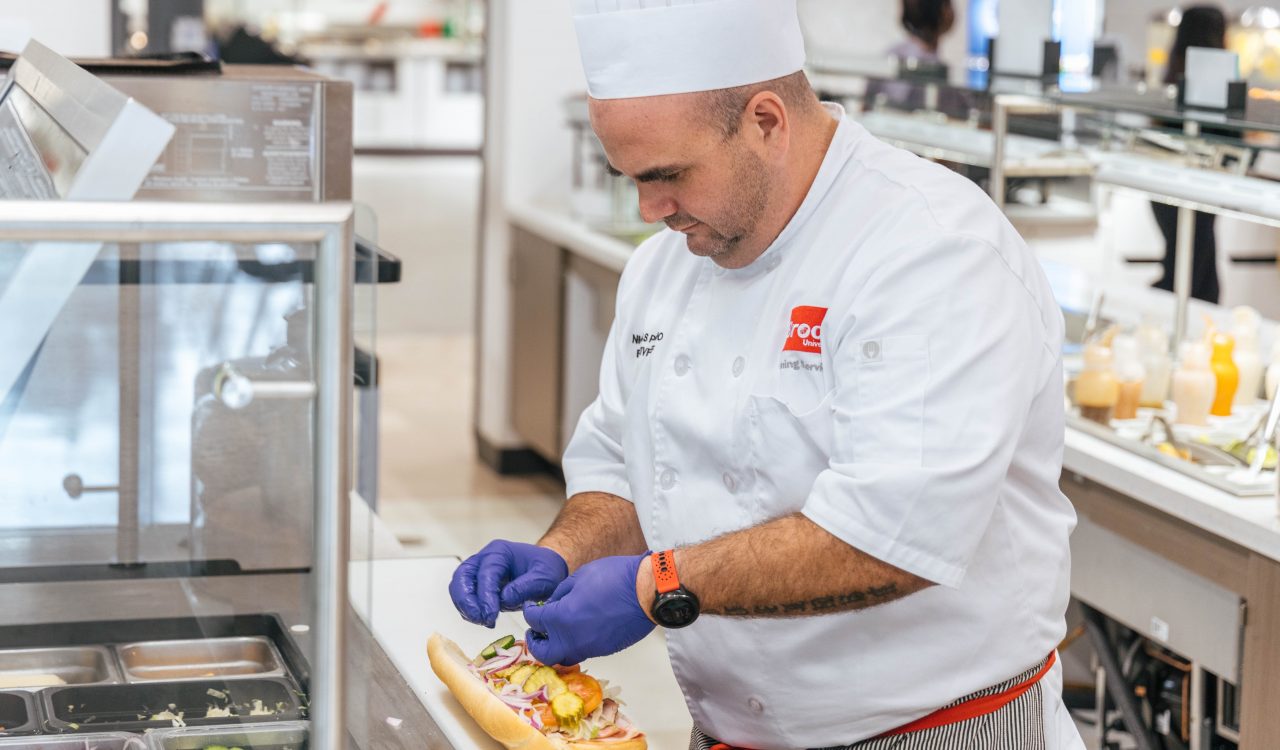 A chef makes a sandwich in an indoor kitchen.