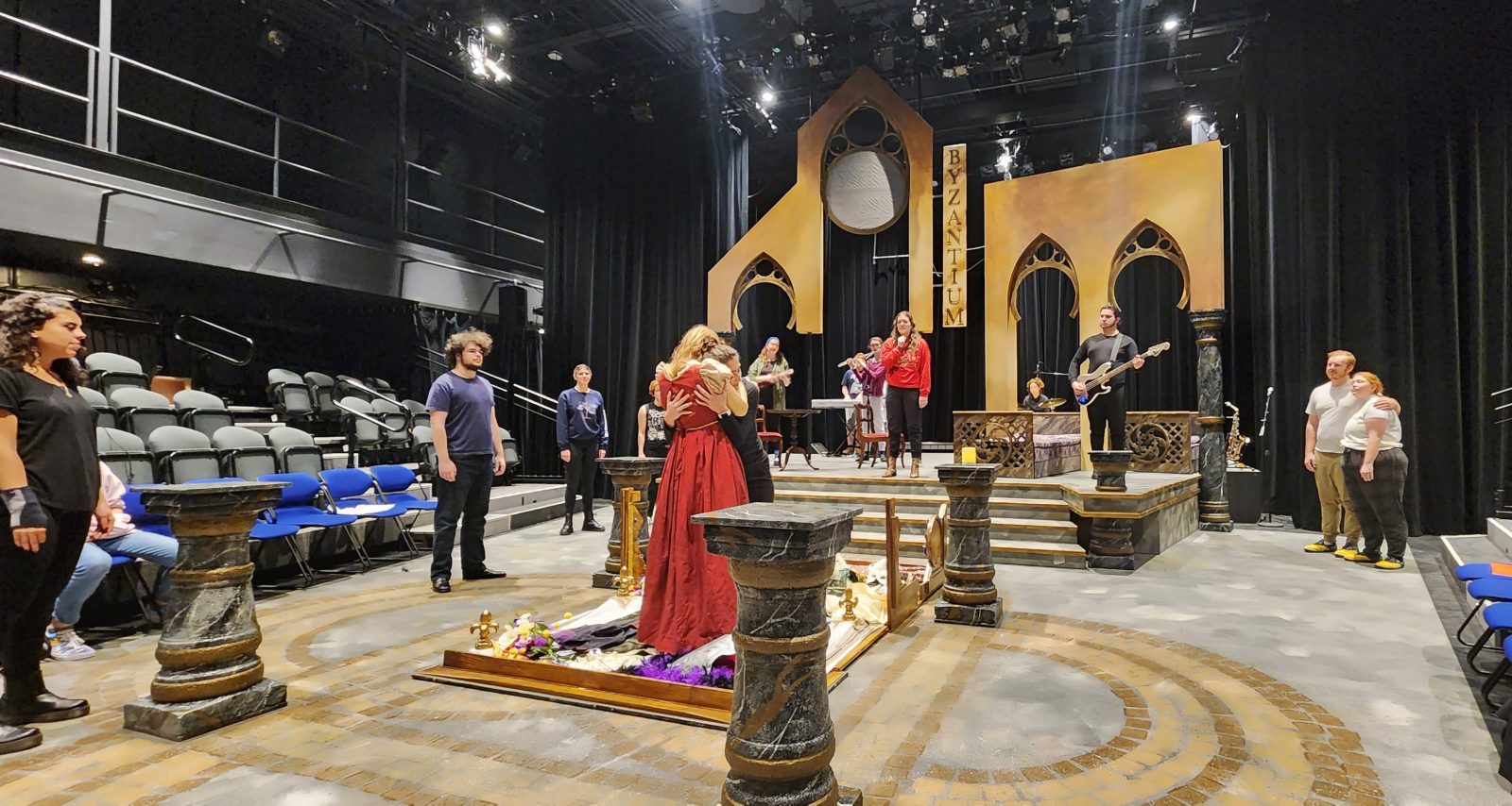 A group of students rehearsing a play circled around a theatre set.