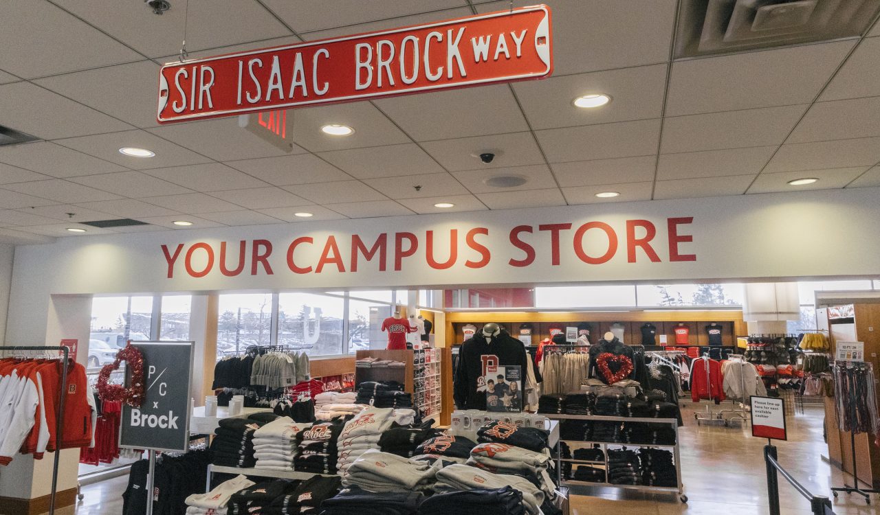 A retail store with a sign that reads 'Your Campus Store' above clothing on tables and shelves.