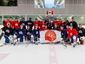 The Brock University Badgers men’s hockey team poses on a sheet of ice holding the United Way flag.