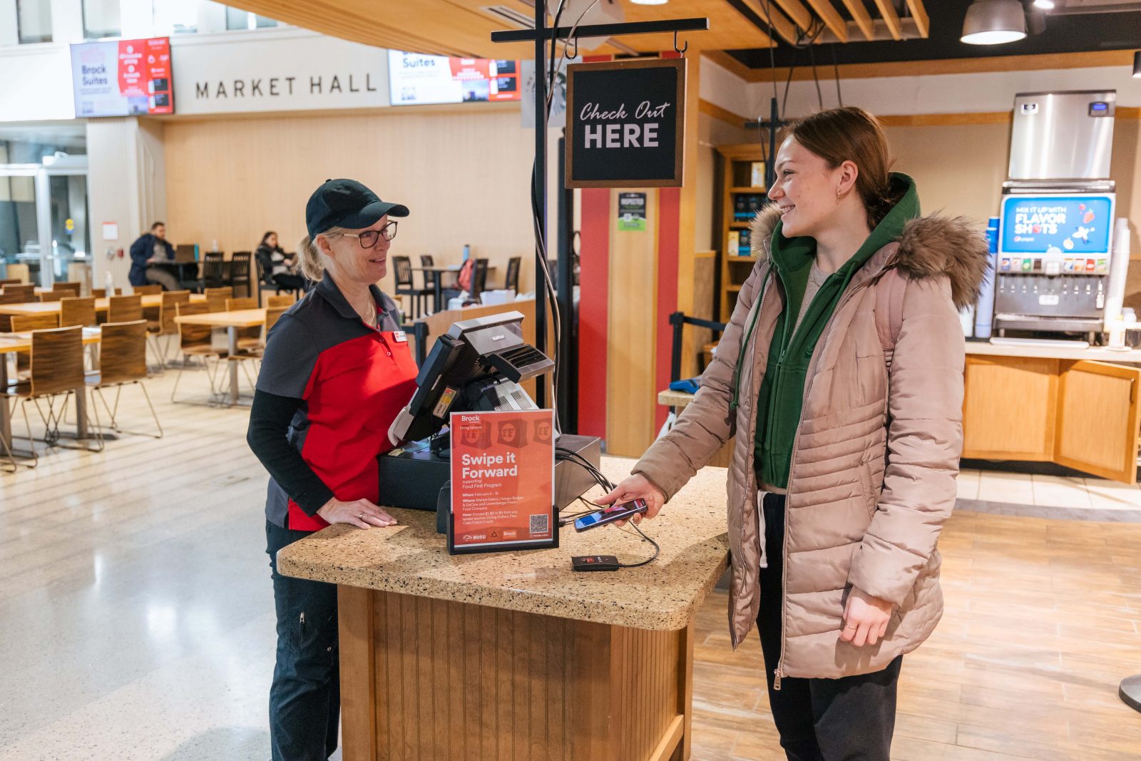 A Brock student and Brock Dining Services retail associate complete a cellphone payment transaction at the Market Eatery.