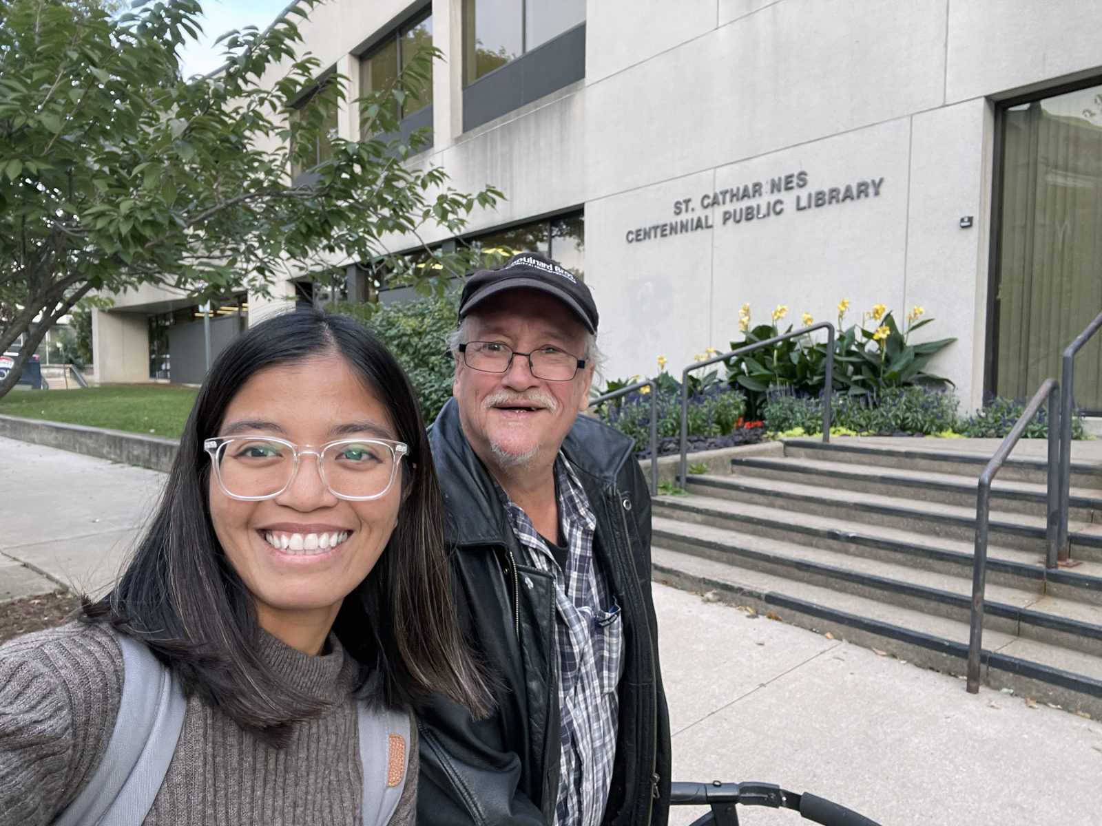 A selfie of Brock University Master of Applied Gerontology student Ella Laygo and Niagara Regional Housing resident Joseph Comeau taken outside the St. Catharines Public Library.