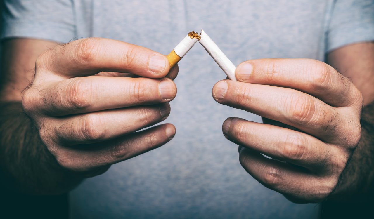 A man's hands breaking a cigarette in half.