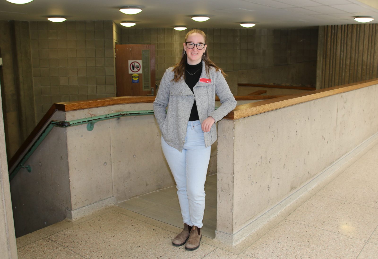 A woman stands in front of an indoor ramp leading to a lecture hall.