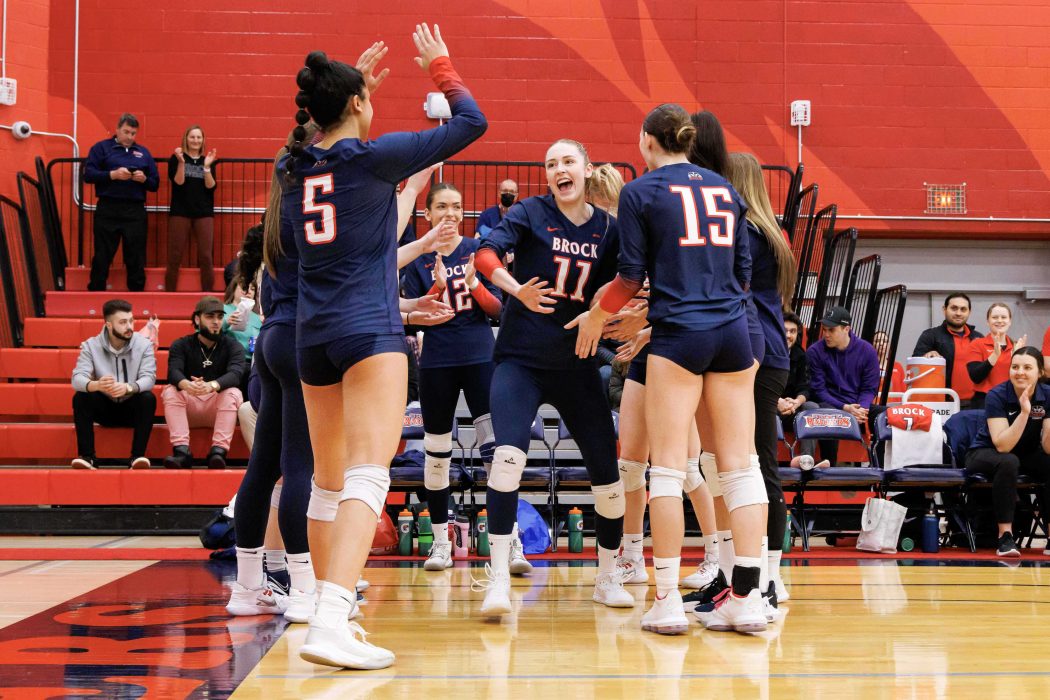 A group of volleyball players celebrate on the court.