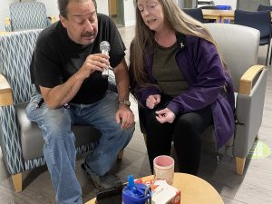 Niagara Regional Housing residents Randy Burgess and Jaime Robinson are pictured in their building’s common room with a microphone and singing a duet, at a Karaoke Night hosted Oct. 27, 2022 as part of the Intergenerational Community — Engaged Residency activities program.