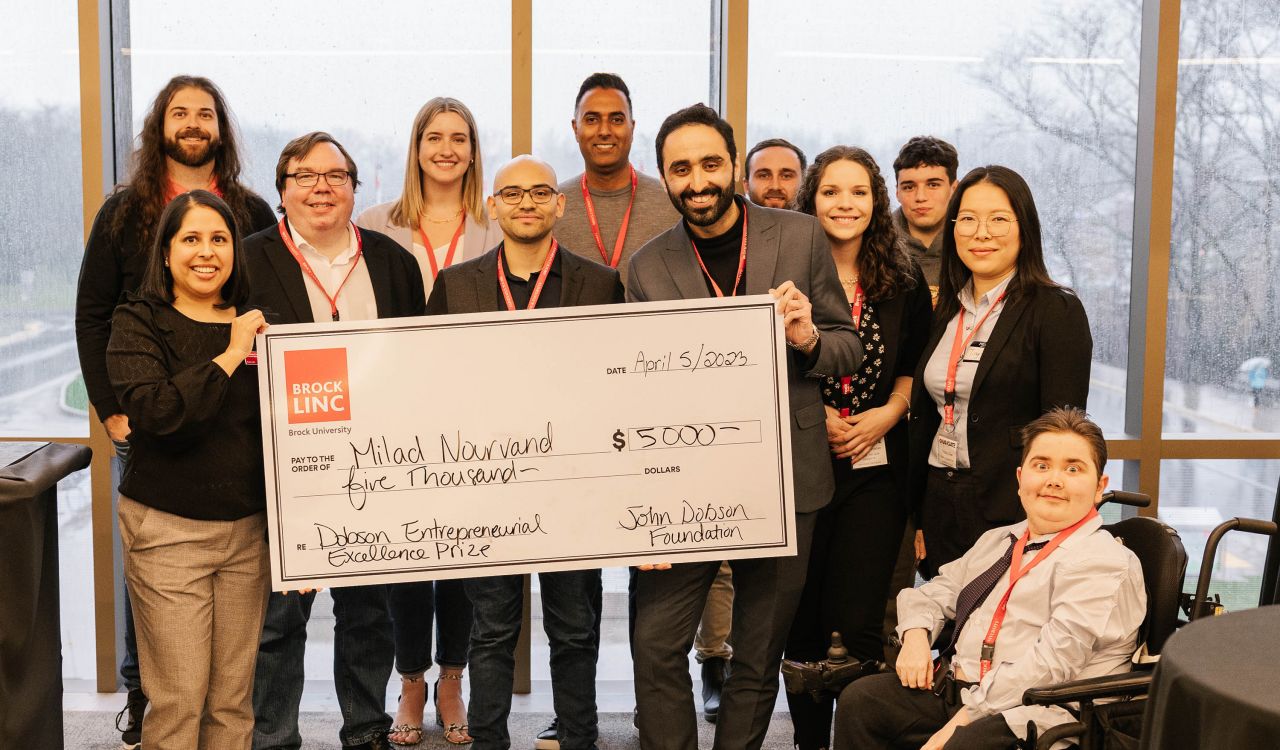 A group of people hold a presentation cheque at a pitch competition.