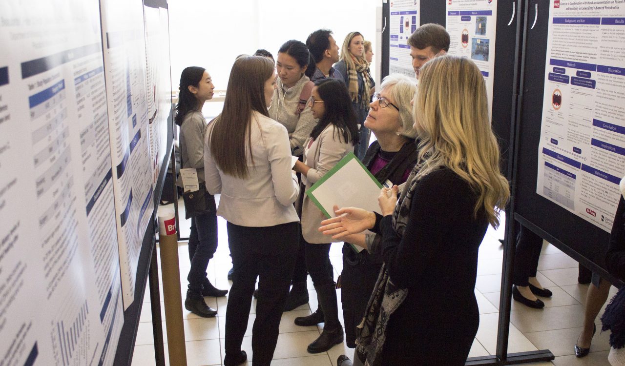 Nearly a dozen people gather to look at several poster presentations focused on health research by Brock University students.
