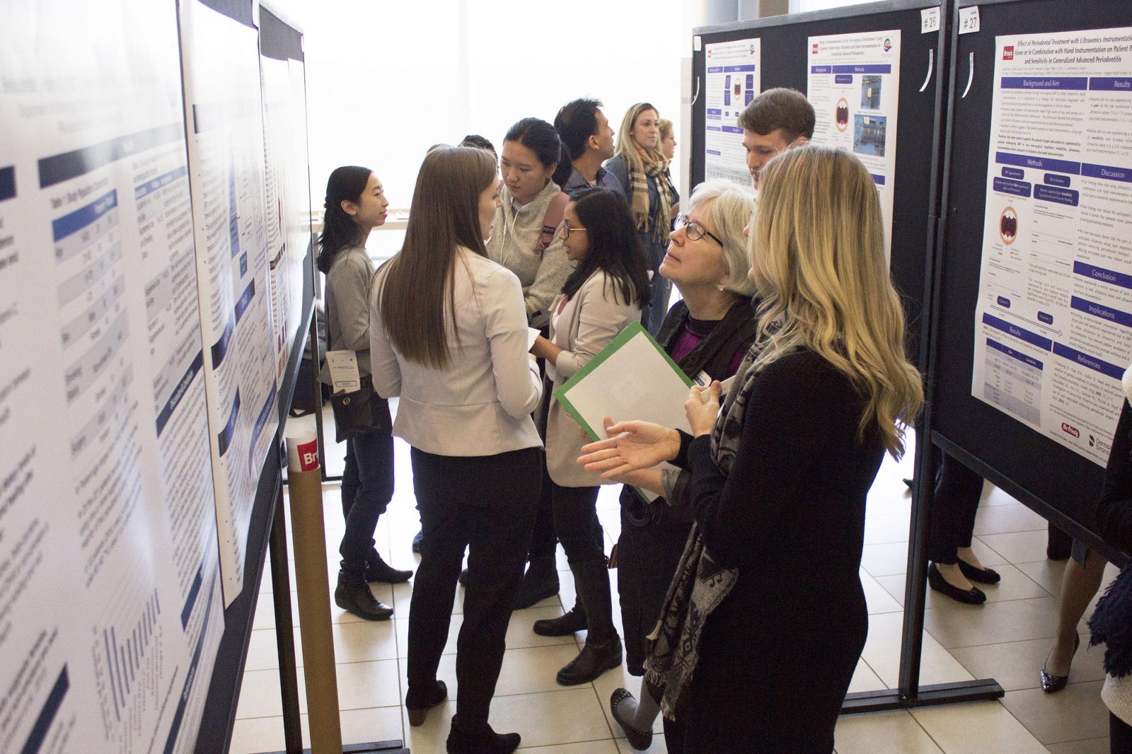 Nearly a dozen people gather to look at several poster presentations focused on health research by Brock University students.