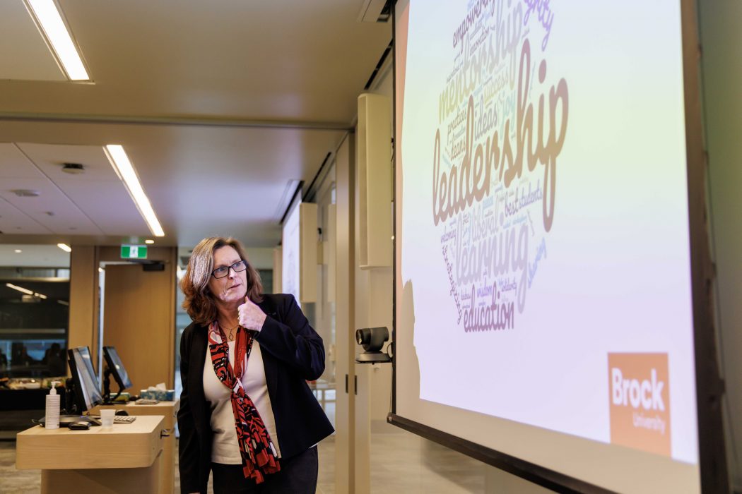 During a presentation, President Lesley Rigg looks at a projected slide showing a word cloud with the word “leadership” highlighted in the centre.