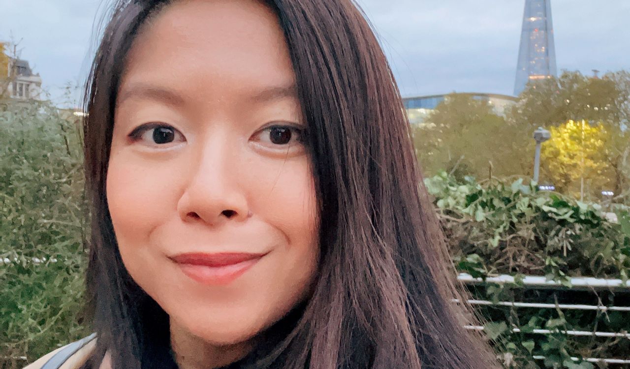 Close-up portrait of Rachel Song taken outside with a city in the distance. She is wearing a light brown jacket and black shirt.