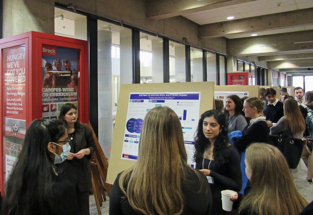 People crowd into an indoor university hallway.