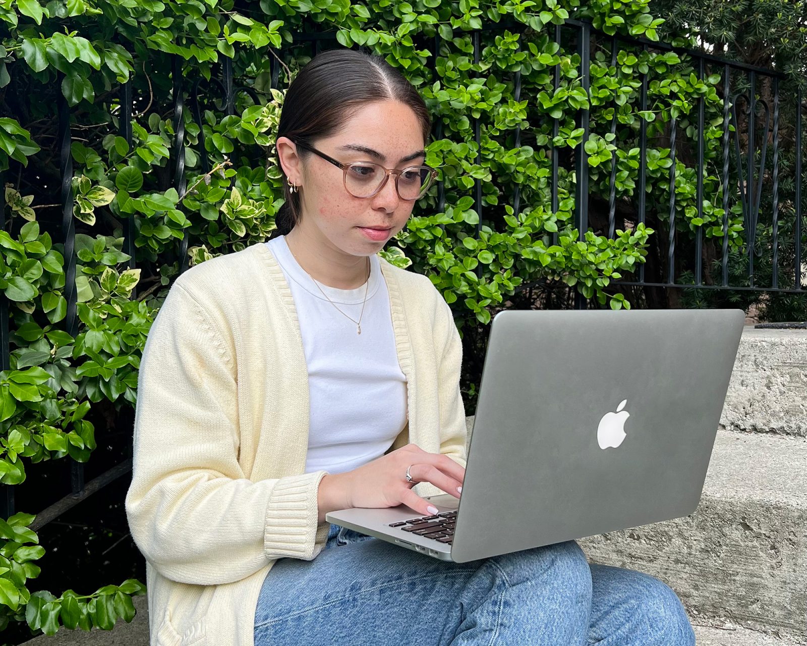Brittany Giles sits on outdoor steps with a laptop computer on her lap.