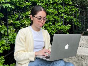 Brittany Giles sits on outdoor steps with a laptop computer on her lap.