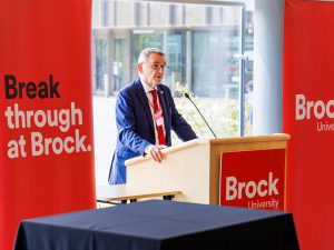 A man standing behind a podium speaks at a reception at Brock University..
