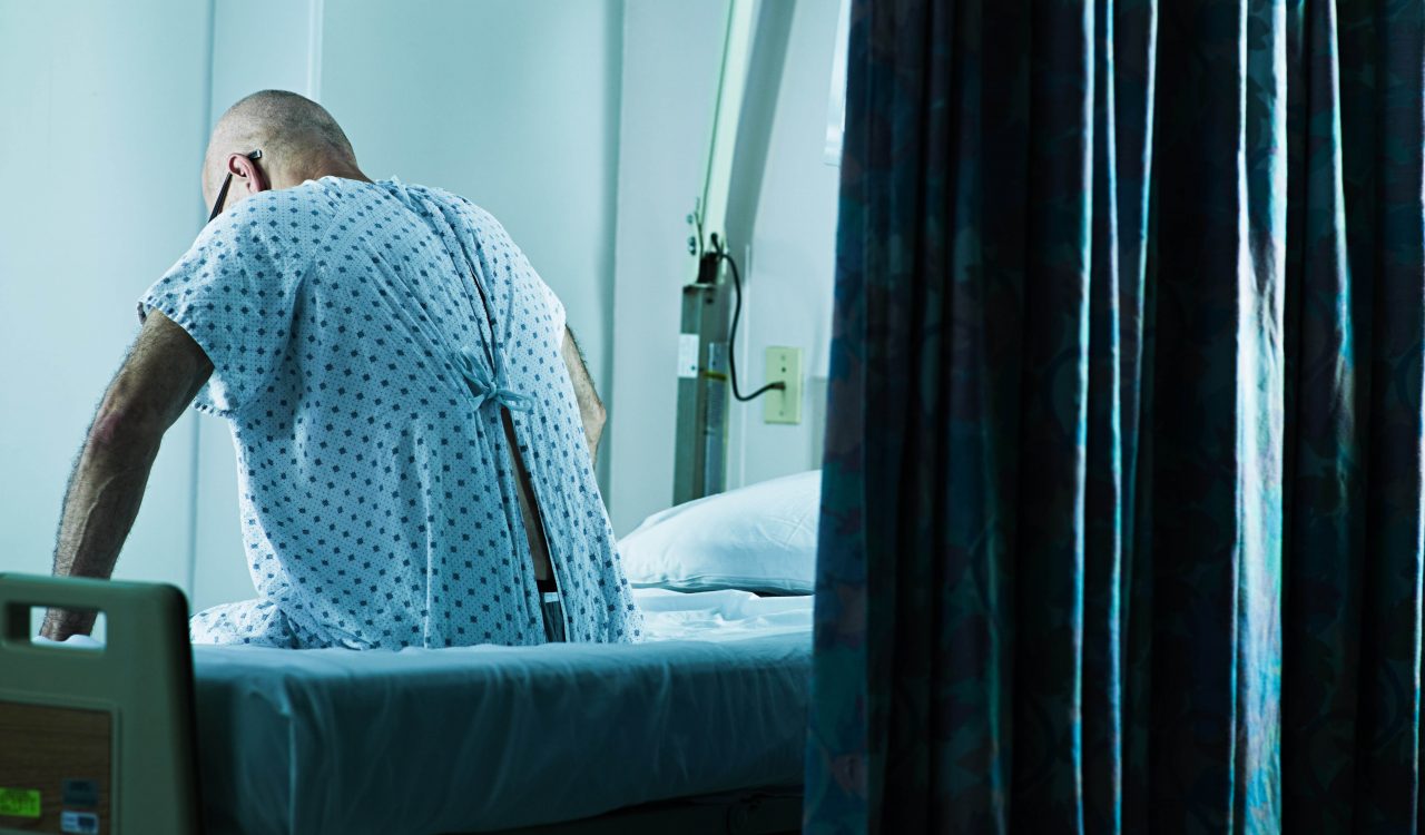 A man sits on a hospital bed.