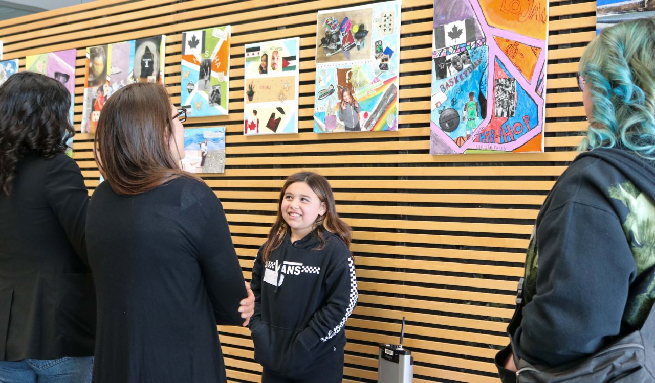 A child shows her artwork to Brock University employees while her mom listens in.