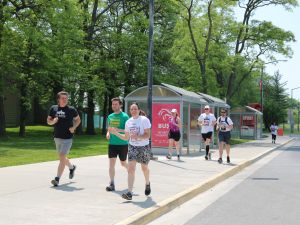 A group of runners run along an outdoor sidewalk at Brock University.