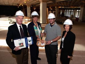 Four people wearing hard hats stand in a construction zone in the Brock University James A. Gibson Library.