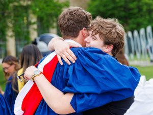 A young man in graduation robes hugs a loved one at Brock University's Convocation.
