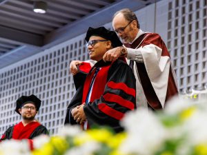 A faculty member places a hood on a new Brock University graduate at Convocation.