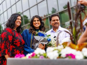 A new Brock graduate poses with loved ones outside while holding a bouquet of flowers.