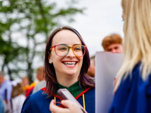 A new Brock graduate smiles at a friend outside after Convocation.