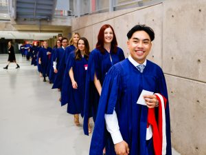 A line of graduating students in robes walk into a Brock University Convocation ceremony.