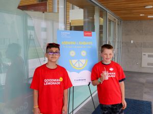 Two students pose beside the 'Goodman Lemonade' sign, sponsored by FirstOntario Credit Union.