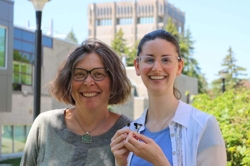 Professor of Biological Sciences Miriam Richards stands beside Master of Science student Jocelyn Armistead, who is holding two pinned bee specimens.