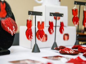 Jewelry shaped like red dresses sits on a table.