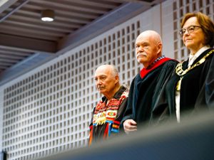 Three people stand side-by-side on stage during a Brock University graduation ceremony.