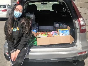 Silvana Nguyen leans on the open trunk of her hatchback, which is packed with food donations. 