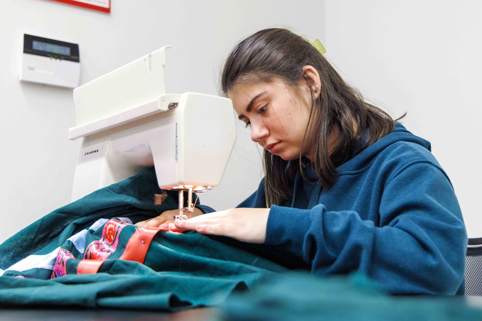 A woman sews a traditional Indigenous skirt using a sewing machine.