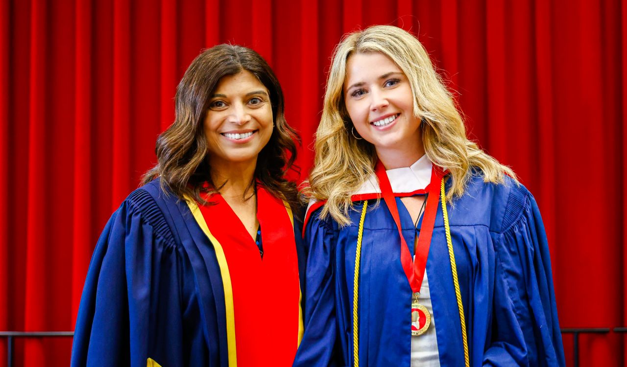 Two women stand side-by-side in academic robes.