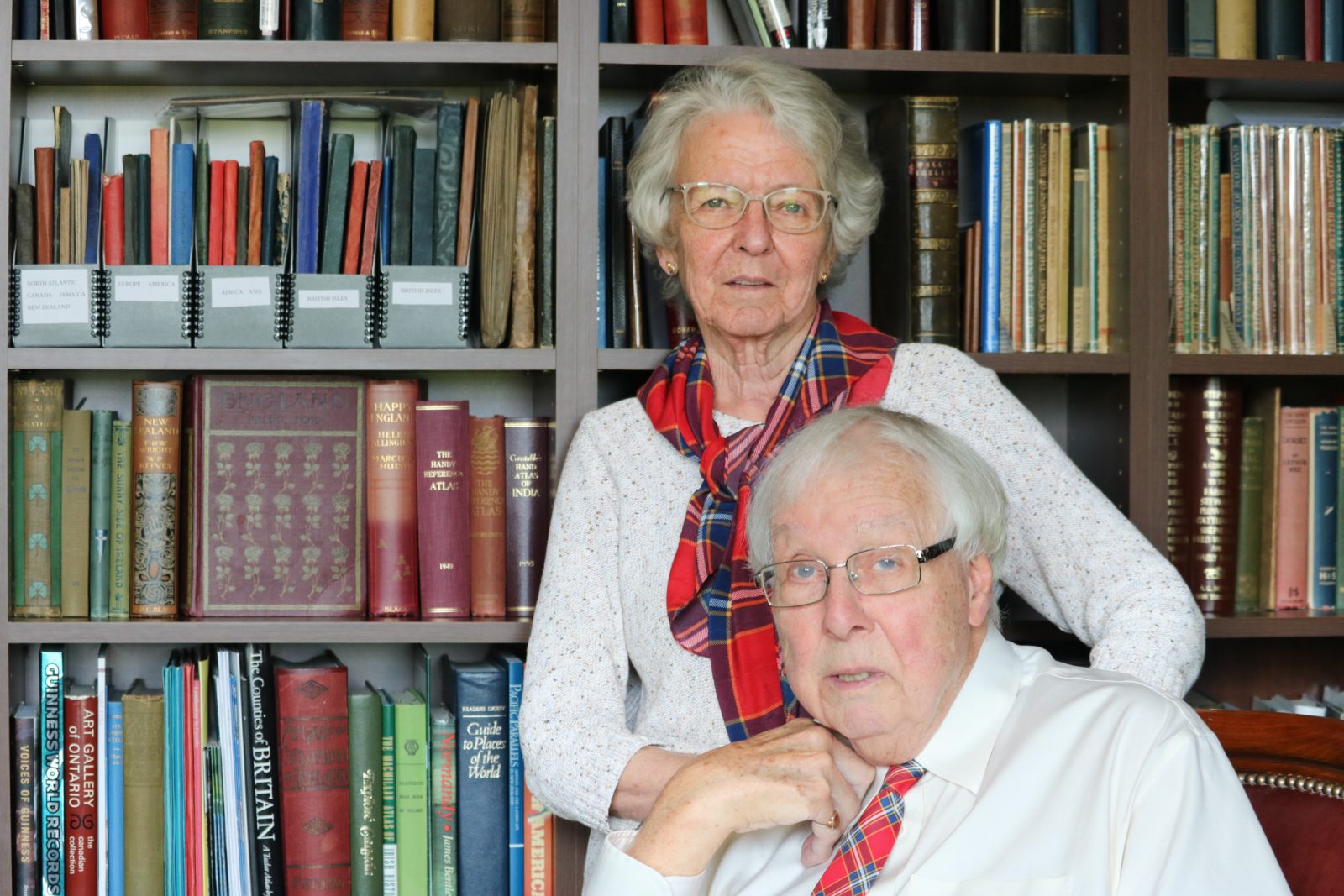David Murray and Elizabeth Surtees pose in their personal library. Murray is wearing a Brock University tartan tie and Surtees the Brock tartan scarf.