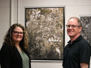 A woman and a man stand on either side of a large historical map of St. Catharines from 1934.